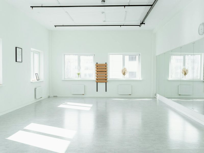Bright minimalist training studio with white walls and wooden floor.