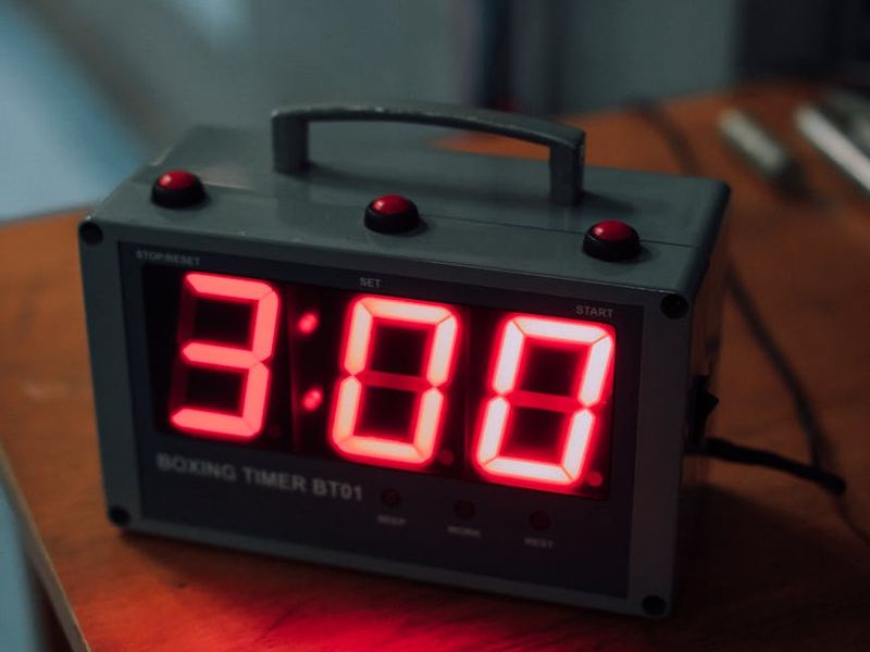 Close up of sports shoes and a stopwatch on a clean floor.